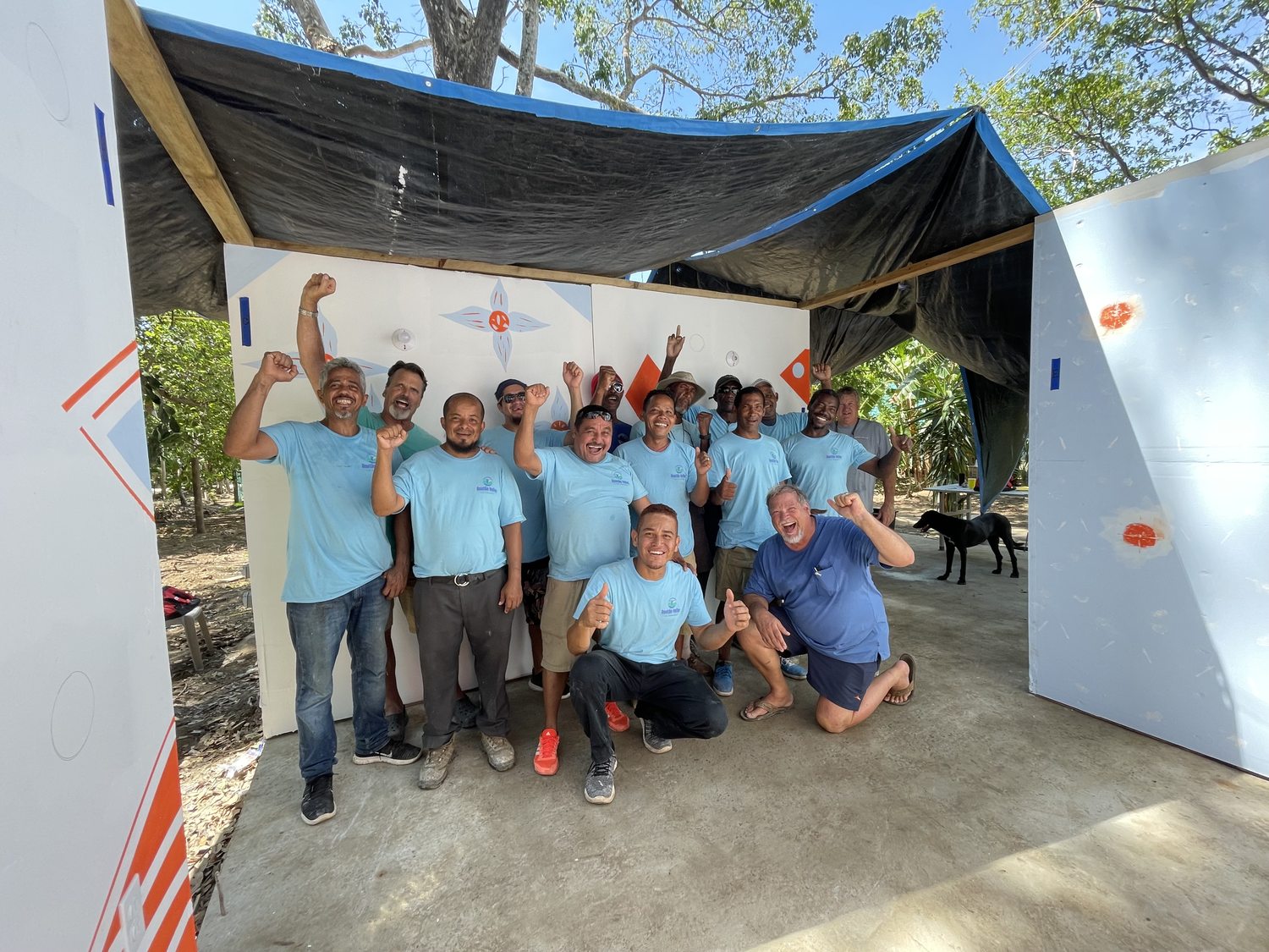 RVT students and volunteers celebrating with fists raised inside the newly completed classroom walls