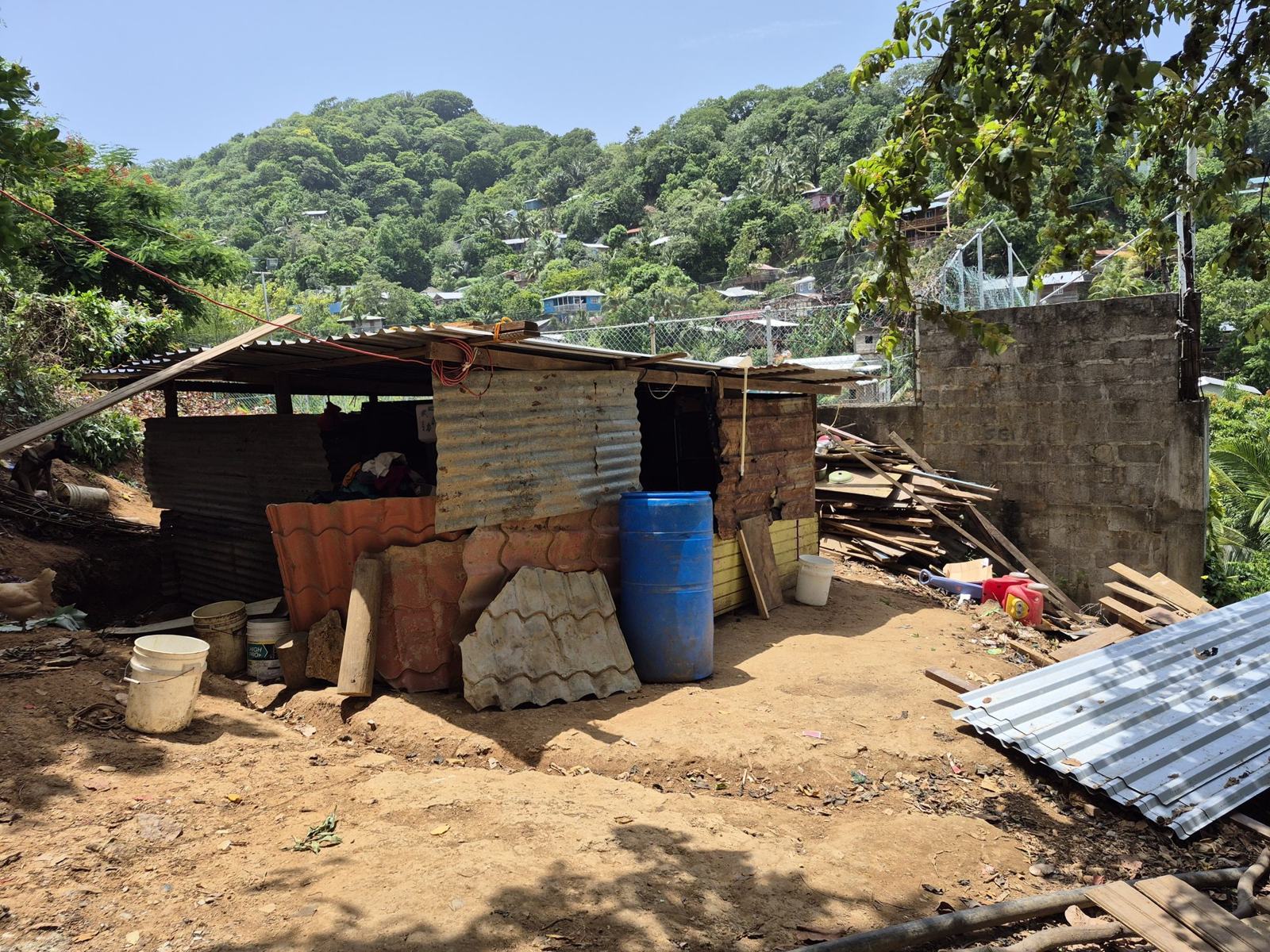 A small shelter of corrugated tin and scrap wood on a dirt hillside