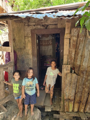 Children standing in the doorway of Candida's scrap-wood home in Roatán